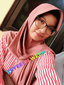 a woman wearing glasses and a hijab has the word keyeeen written on her sleeve