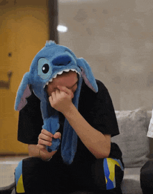 a person wearing a stitch hat covering their face with their hand