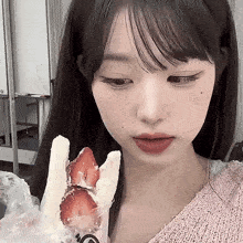 a young girl is holding a sandwich with strawberries on it .