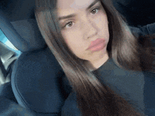 a woman with long hair is sitting in the back seat of a car and making a funny face .