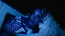 a woman in a blue and white outfit laying in a car