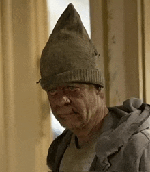 a man wearing a dirty hat and a dirty jacket