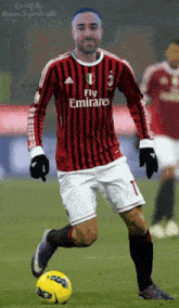 a soccer player wearing a fly emirates jersey kicks a yellow ball
