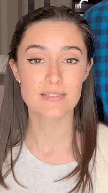 a close up of a woman 's face with long hair and a blue plaid shirt .