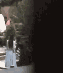 a woman in a white dress is walking down a street in the dark .