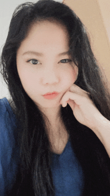 a woman with long black hair and a blue shirt is taking a selfie