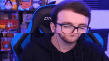 a man wearing glasses and headphones is sitting in a blue dx chair