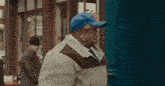 a man wearing a blue hat and a jacket is standing in front of a store