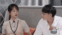 a man and a woman are sitting next to each other and the man is wearing glasses and the woman is wearing a vest