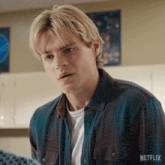 a man in a plaid shirt is standing in front of a netflix sign .