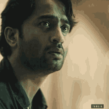a close up of a man 's face with the name tanuja on the bottom left