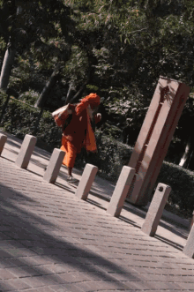 a man in an orange robe is walking down a brick sidewalk