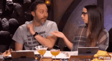 a man and a woman are sitting at a table talking to each other .