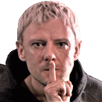 a man holds his finger to his mouth in a shhh gesture
