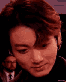 a close up of a man 's face with a man in a suit behind him .