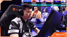 a man wearing headphones sits in front of a computer screen with replay in the corner