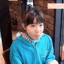 a girl wearing a blue sweatshirt with the letter t on the front