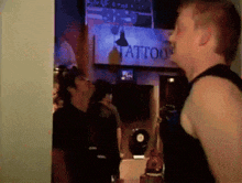 a man stands in front of a sign that says tattoo on it