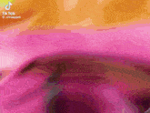 a close up of a pink and orange background with a blurred image of a person 's face .