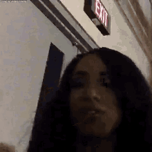 a woman is standing in front of an exit sign in a dark room .