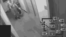 a black and white photo of a person walking down a hallway with a map showing the cameras
