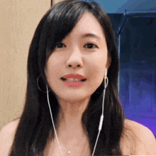 a close up of a woman wearing earbuds and smiling