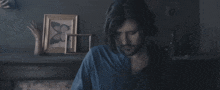 a man in a blue shirt holds his head in pain
