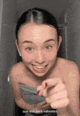a woman with a towel wrapped around her shoulders points at the camera