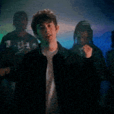 a young man in a black jacket is standing in front of a group of people .