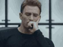 a man is sitting in a chair with his hand on his chin and his eyes closed .