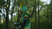 a person in a green and yellow costume stands in the woods