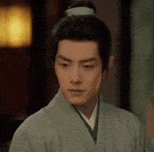 a man with a bun on his head is wearing a kimono .