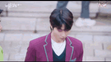 a man in a purple suit is standing on a sidewalk .