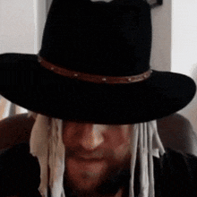 a man wearing a black cowboy hat with a brown band