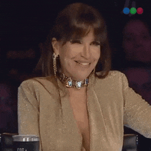 a woman wearing a gold top is smiling and holding a cup that says pot