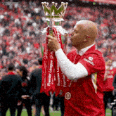 a man in a red shirt with expedia on it kisses the trophy