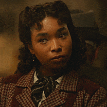 a close up of a woman 's face wearing a plaid jacket