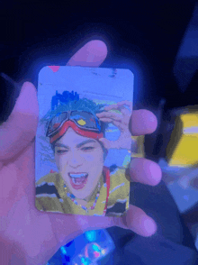 a person is holding a card with a picture of a man wearing goggles