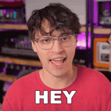 a man wearing glasses and a red shirt is saying hey