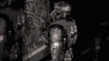 a black and white photo of a soldier in armor holding a gun .