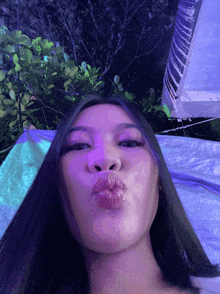 a woman blowing a kiss in front of a purple background