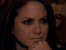 a close up of a woman 's face with a ring on her finger and the name liz written on the bottom right