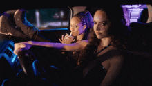 two women are sitting in a car at night and one is holding a drink