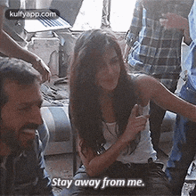 a woman is sitting in a room with a group of people and a man is talking to her .