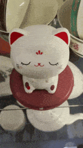 a white cat with red ears is sitting on a red circle