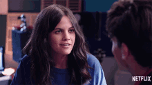 a woman in a blue shirt is smiling next to a man in a red shirt with the word netflix on the bottom