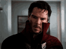a close up of a man wearing a red coat with a brooch on his chest .