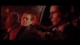two men are standing next to each other in a dark room .