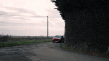 a red car is driving down a country road with a sign that says c8 on it