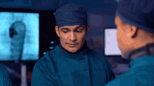 a man in a surgical gown talks to another man in an operating room